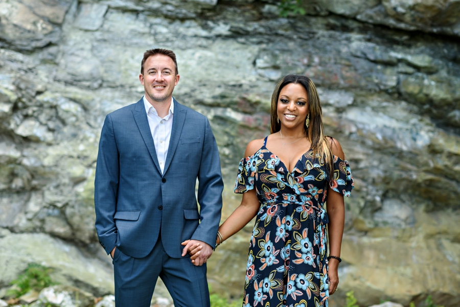 A couple hold hands in front of giant boulders in Hoboken.